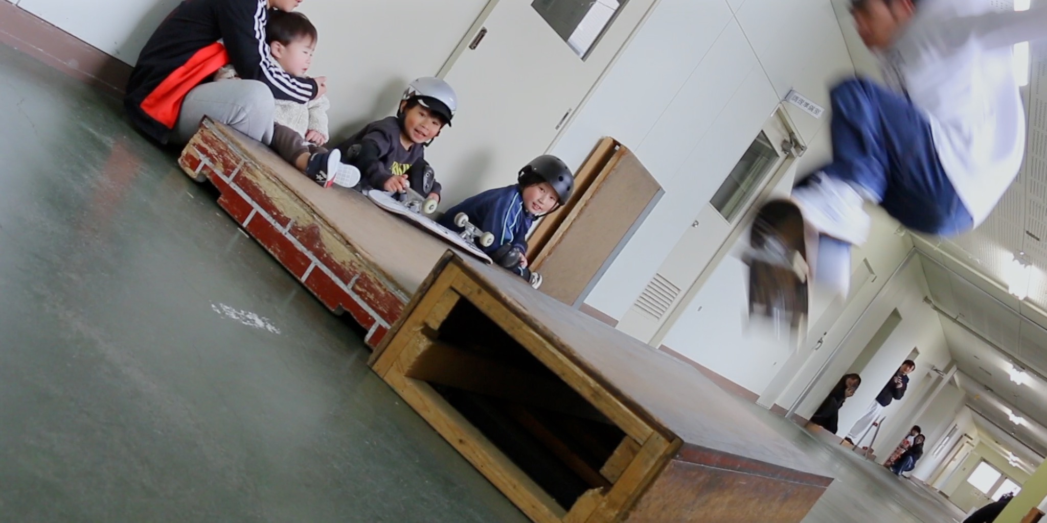 ボックスのそばで順番を待ちながら仲間の滑りを見つめる子どもたち