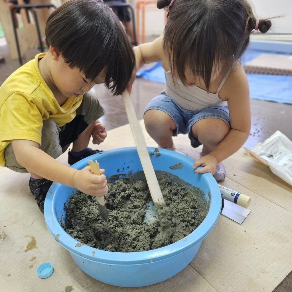 子どもがモルタルを混ぜて改装を手伝う様子