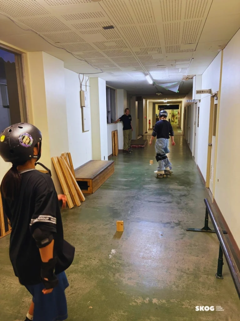 廊下の奥へ滑っていく参加者を見守る子ども